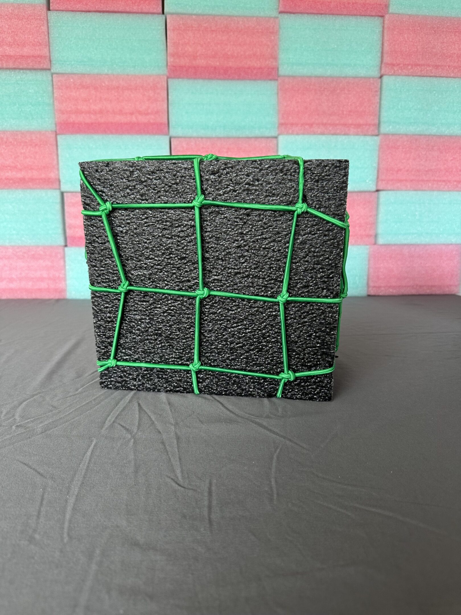 A textured black block with green grid lines on a gray surface.