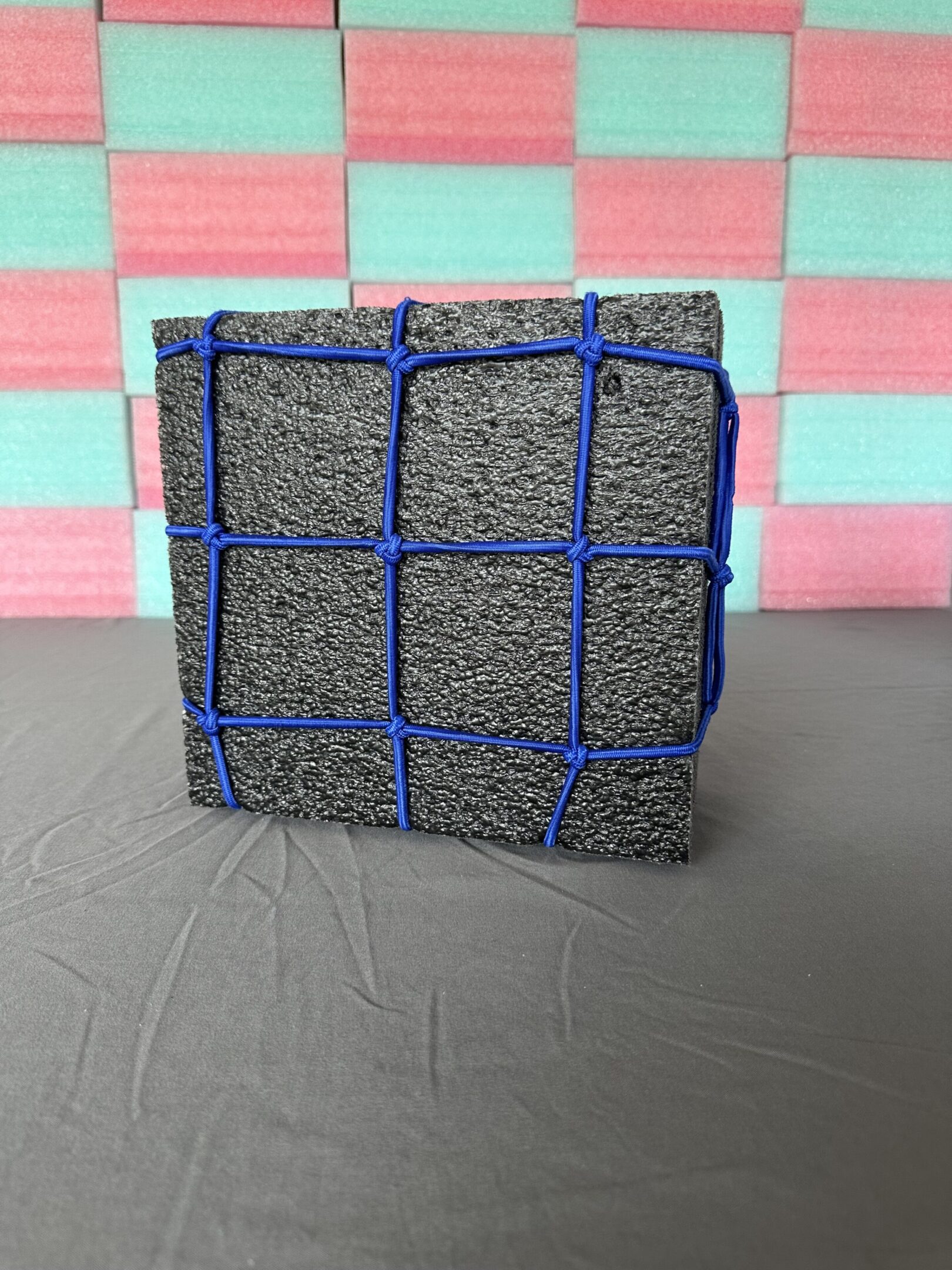 A dark block secured with blue netting on a table.
