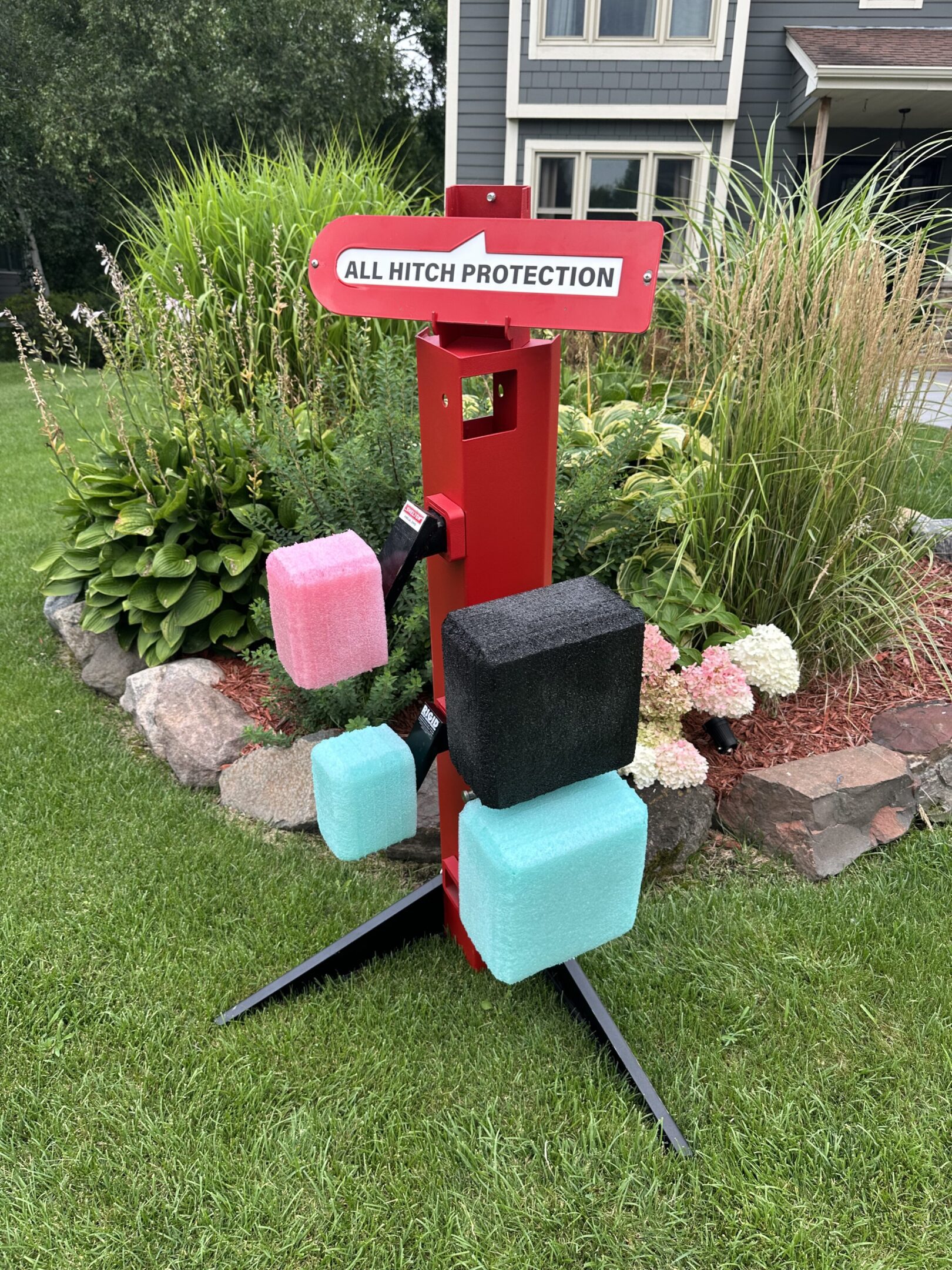 Colorful outdoor mailbox stands on green lawn with plants.