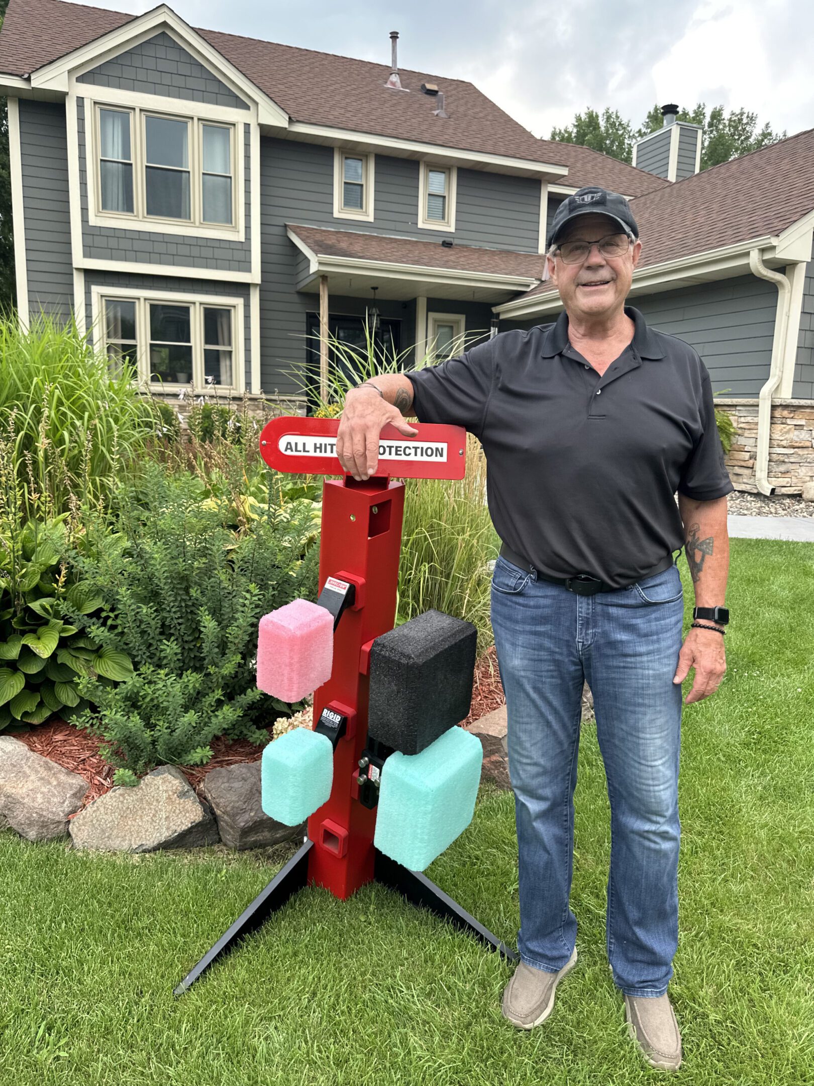 Man standing next to a red sanitizer and mask dispenser outdoors.