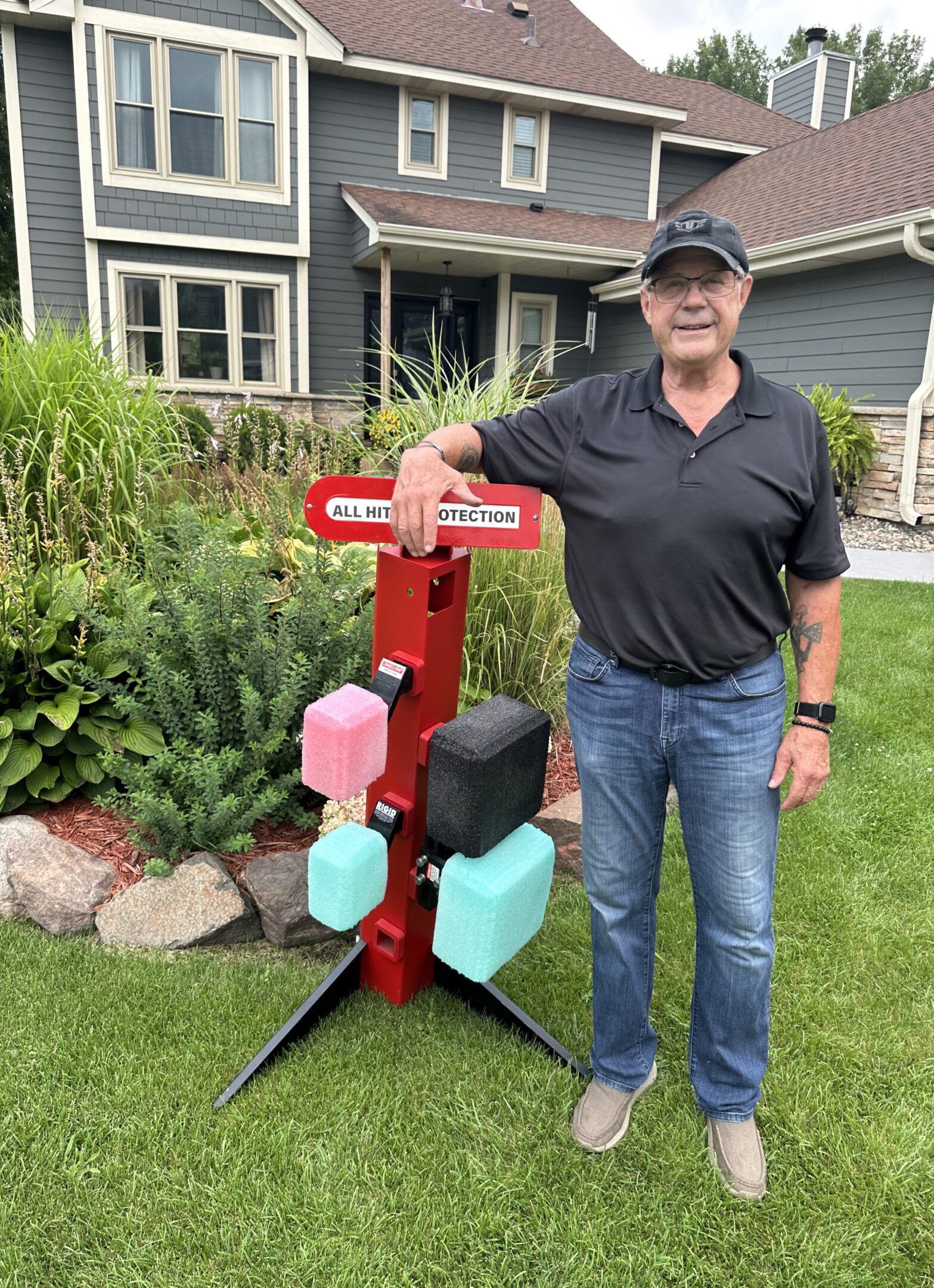 Man posing with a colorful mailbox stand in front of a house.